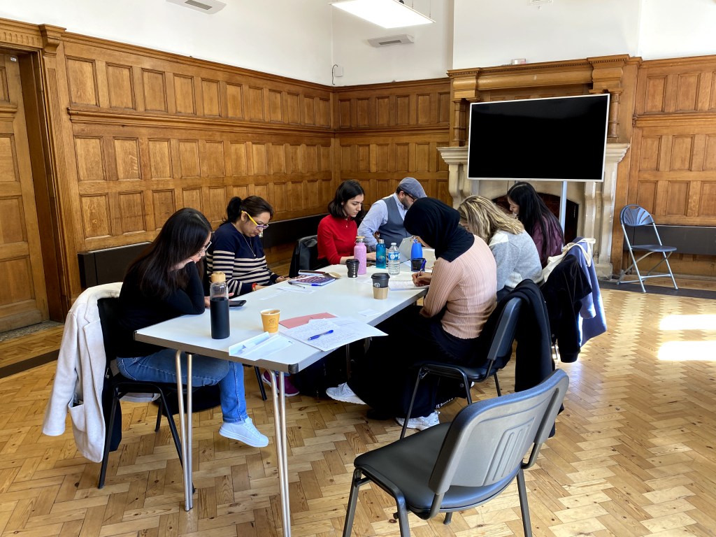 The writers and organizers of migrant projects sitting around a table writing.